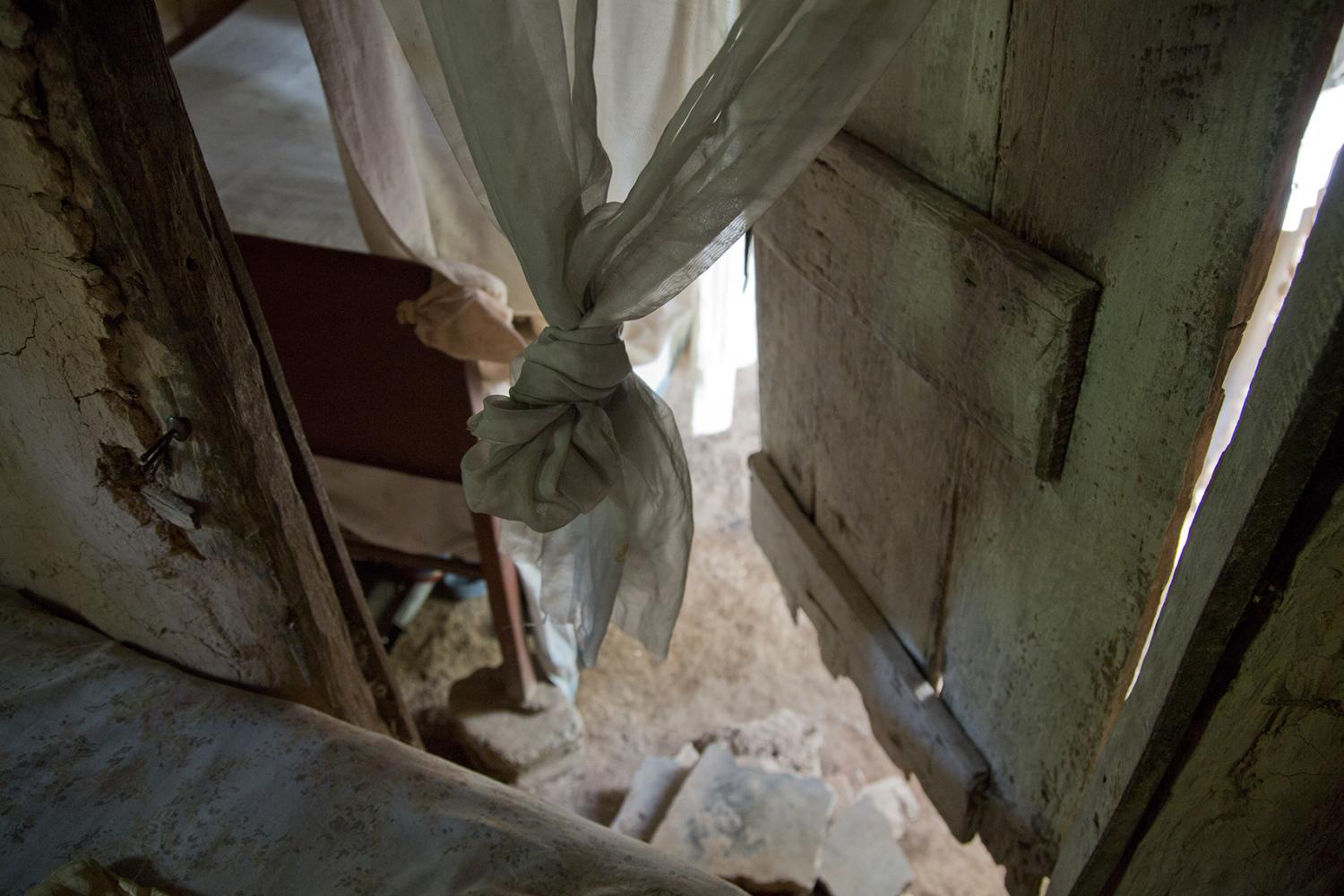 Window curtains and shutter in a home in Milot, Haiti.