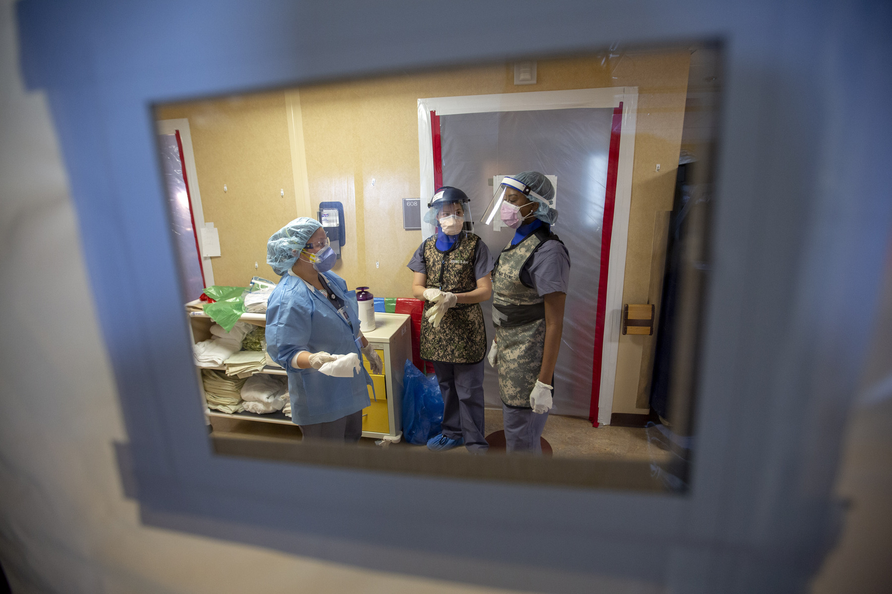 X-Ray technologists donning PPE, seen through a plastic doorway, during the COVID-19 Pandemic at Holy Name Medical Center in Teaneck, New Jersey. 03/19/2020. Photo by Jeff Rhode/Holy Name Medical Center
