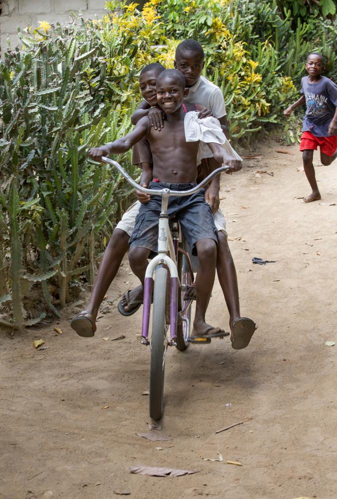 3 children ride a bicycle in Milot, Haiti.