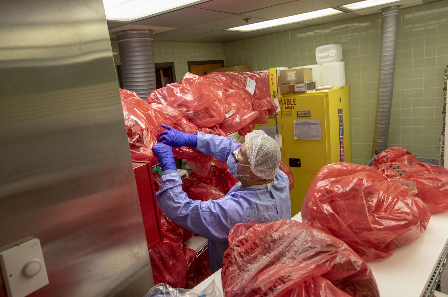 A histologist looks for patients belongings to return to family members in the morgue during the COVID-19 pandemic. 5/6/2020 Photo by Jeff Rhode